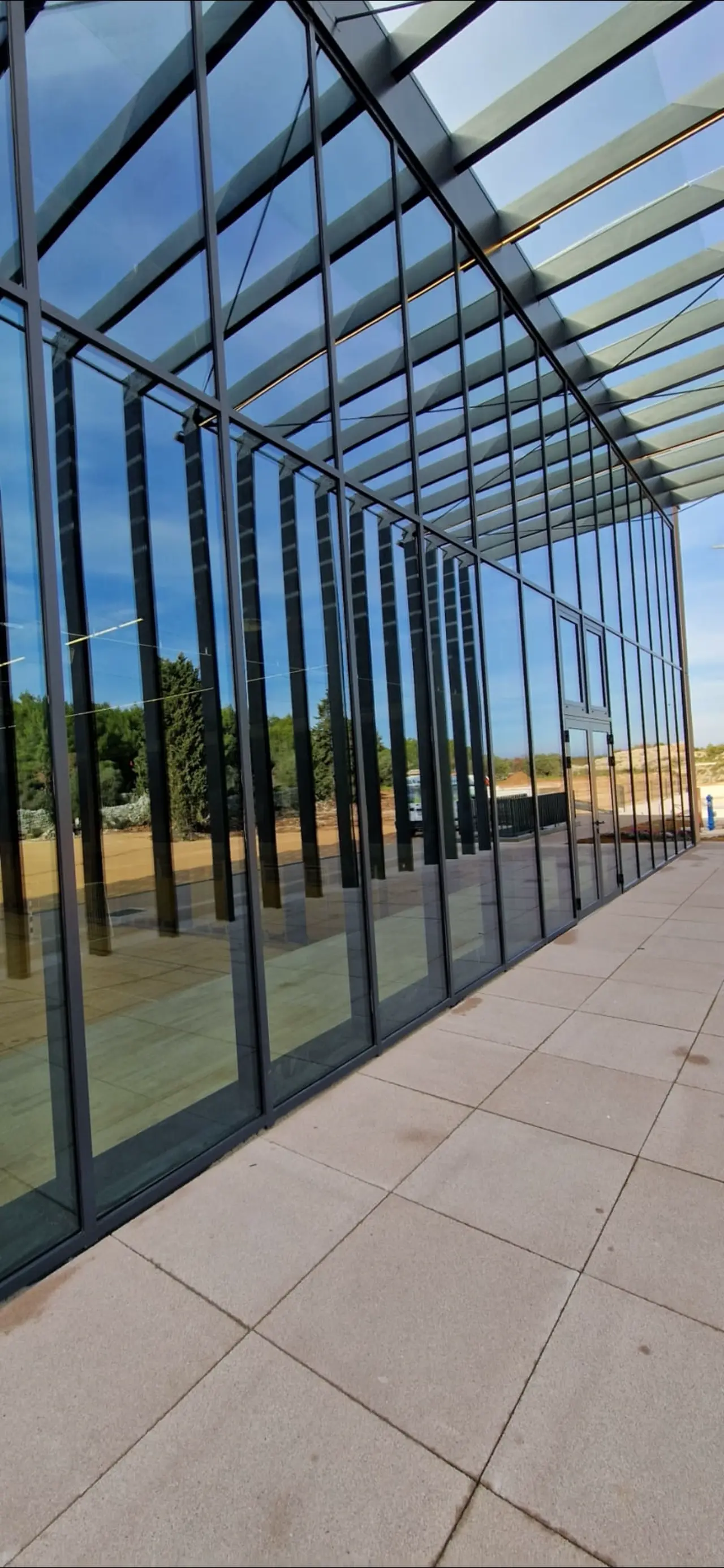 Besprijekorno očišćena velika staklena fasada modernog arhitektonskog objekta pod vedrim nebom.