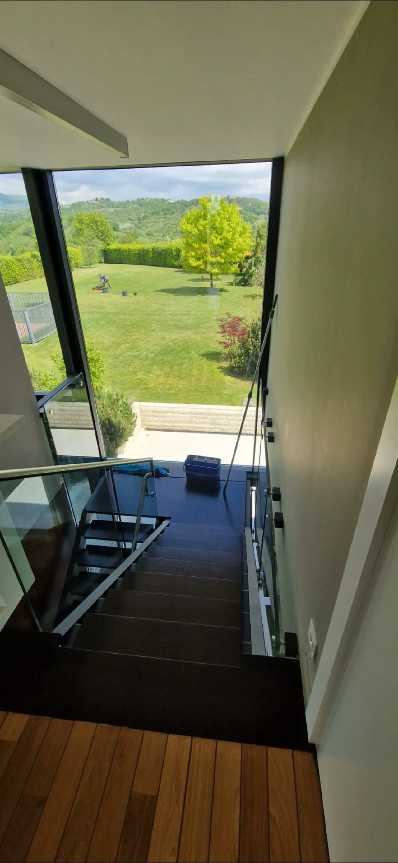 Pogled na besprijekorno očišćeno moderno stubište s drvenim gazištima i velikom staklenom stijenom u Zagrebu.